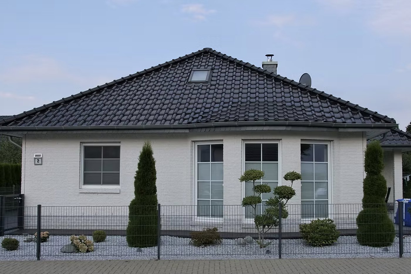 Fertiggestellter Bungalow mit dunklem Dach und gepflegtem Vorgarten
